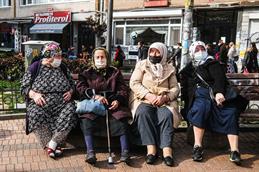 Eine Straßenszene in Istanbul. Vier Frauen sitzen nebeneinander auf einer Bank und unterhalten sich.